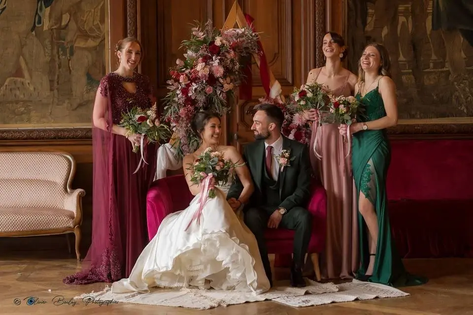 Mariée et marié entourés de leurs témoins dans un salon boisé, bouquets bordeaux et rose poudré et arche fleurie composés par Mily Fleurs